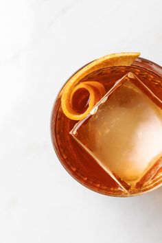 an overhead view of a drink in a glass with orange peels on the rim