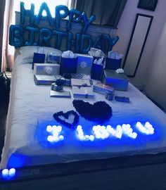 a bed topped with lots of blue and white gifts next to a happy birthday sign