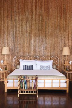 a bed sitting on top of a wooden floor next to two tables with lamps around it