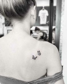 a woman with a butterfly tattoo on her upper back shoulder and behind her left arm