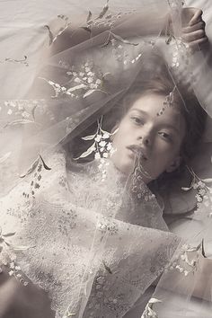 a woman laying on top of a bed covered in flowers