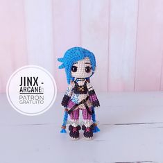 a crocheted doll with blue hair standing on a white table next to a pink wall