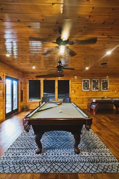 a pool table in the middle of a room with wood paneling and ceiling fans