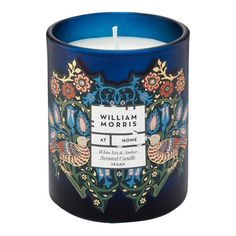 a blue candle with an ornate design on the top and bottom, in front of a white background