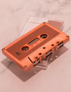 an orange cassette tape recorder sitting on top of a marble counter next to a pair of scissors