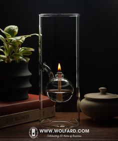 a glass teapot with a candle in it on a table next to some books