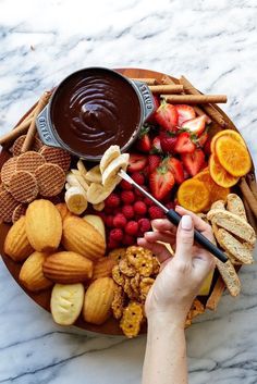 a platter filled with fruit, crackers and chocolate sauce