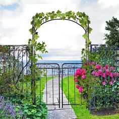 an iron gate with pink flowers in the foreground and water in the back ground