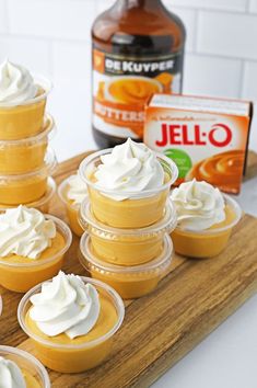 cupcakes with whipped cream on top sitting on a cutting board next to a bottle of jello