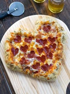 a heart shaped pizza sitting on top of a wooden cutting board