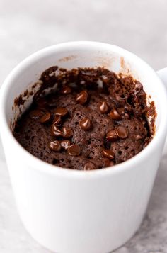 a white cup filled with chocolate pudding and topped with lots of chocolate chips on the side