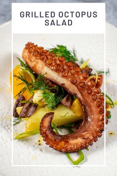 grilled octopus salad on a white plate with green garnish