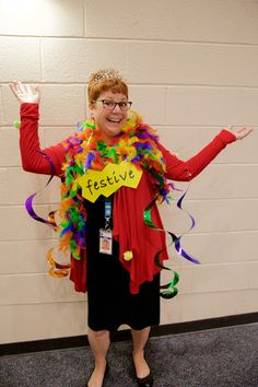 a woman dressed up as a mardi gras clown with her hands in the air