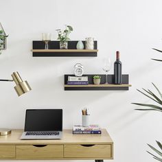 a laptop computer sitting on top of a wooden desk next to a potted plant