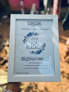 a person holding up a frame with an islamic message