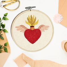 an embroidered heart with wings on it next to some scissors and other crafting supplies