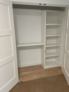 an empty closet with white shelves and doors