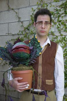 a man holding a potted plant in front of a brick wall