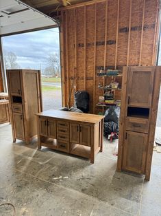 a room that is being remodeled with wooden walls and cabinets on the floor, in front of an open garage door