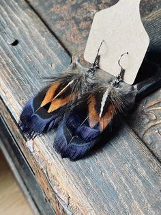 a pair of earrings with feathers hanging from them