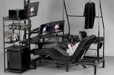 a man laying on a chair in front of two monitors