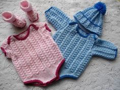 two knitted baby clothes and booties laying on a white tablecloth next to each other