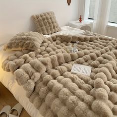 the bed is made with fluffy blankets and pillows