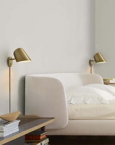 a bed with white sheets and pillows next to a book shelf filled with books on top of it