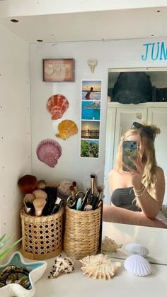 a woman taking a selfie in front of a mirror with shells and seashells