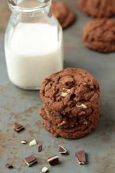 chocolate cookies and milk sitting on a table next to some broken up pieces of cake