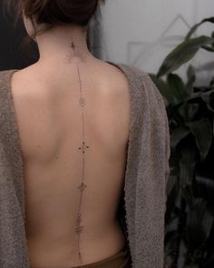 the back of a woman's neck with an arrow tattoo on her left side