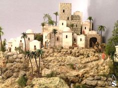 a model of a desert town with palm trees on the rocks and mountains in the background