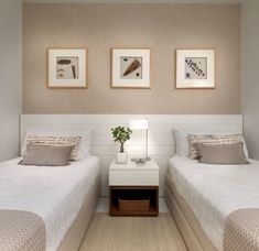 two beds in a room with pictures on the wall