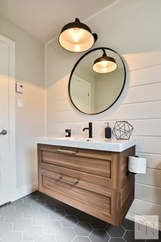 a bathroom with two round mirrors above the sink, and a wooden vanity in front of it