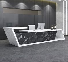 a marble reception table in an office with grey walls and flooring, along with two laptops on the desk