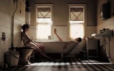 two women sitting in a bathtub with their feet up on the edge of the tub