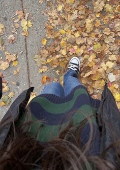 two people standing next to each other with their feet on the ground and leaves all around them