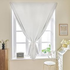 a room with a chair, window and white curtain in the corner on the wall