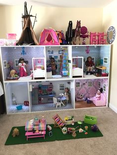 a doll house with lots of furniture and toys on the floor in front of it