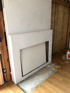 an unfinished fireplace in the corner of a room with wood flooring and construction materials