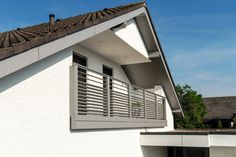 a white house with a brown roof and balcony