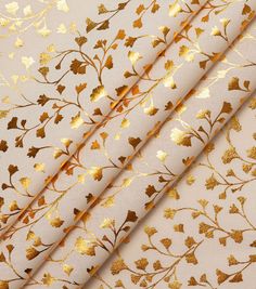 gold foiled leaves on white fabric, with golden metallic leaf designs in the background