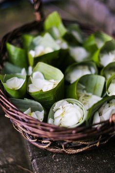 a basket filled with green leaves and white flowers