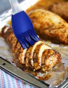 a close up of a brush cleaning chicken on a pan