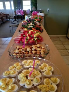 several trays filled with different types of food on top of a long buffet table