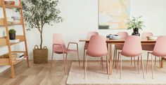 a dining room table with pink chairs and a potted plant