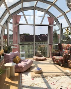 a living room filled with lots of furniture and large glass windows over the top of it