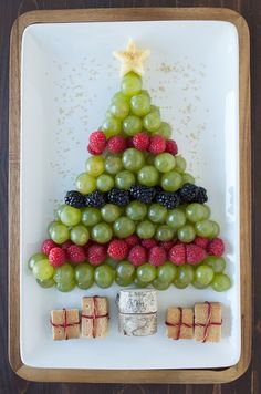 a christmas tree made out of grapes and crackers on a plate with the words create a healthy fruit platter