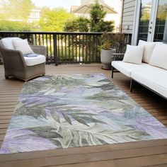 a large rug on a wooden deck in front of a couch and two white chairs