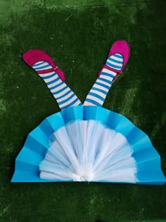 a person in striped socks and pink shoes laying on top of a blue fan